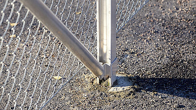 Verkkoaidan alumiinisen tolpan maakiinnitys on tehty valamalla betonilla asfalttiin.