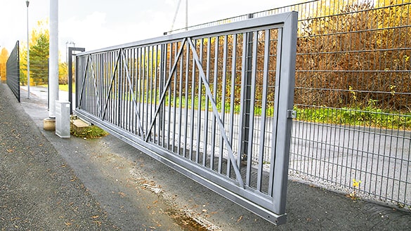 Harmaaksi maalattu säletäytteinen liukuportti auki asennossa.