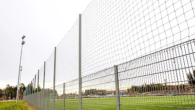Palloilukenttää ympäröi vaalena harmaa elementtiaitaus ja sen päälle asennettu korkea suojaverkko.