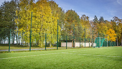 Palloilukenttä on aidattu vihreällä, elementtiaidalla ja korkealla maalintaustaverkolla.