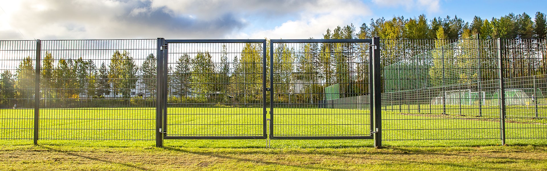 Pallokenttä on ympäröity mustalla elementtiaidalle, jossa on kaksilehtinen saranaportti huoltoajoa varten.