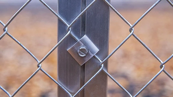 Panssariverkkoaita kiinnitetty alumiiniprofiilitolppaan ruuvilla ja kiinnikelevyllä.