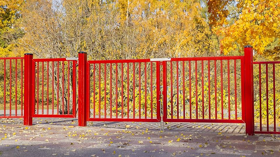 Kirkkaan punainen räätälöity yhdistelmäportti, jossa on kaksilehtinen huoltoportti ajoneuvoille ja yksilehtinen käyntiportti jalankulkijoille.